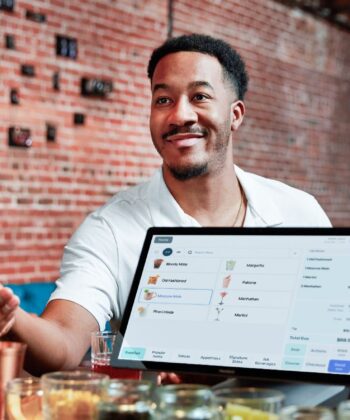 A man and woman smile together while holding a laptop, showcasing a moment of collaboration and joy. - Hausion