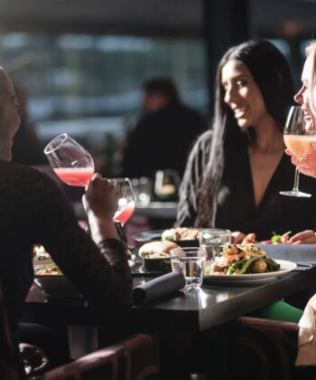 Three women share laughter and delicious food together at a cozy restaurant table, enjoying their meal and each other's company. - Hausion