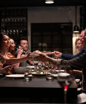 Friends joyfully toasting with drinks at a restaurant, capturing a moment of celebration and camaraderie. - Hausion