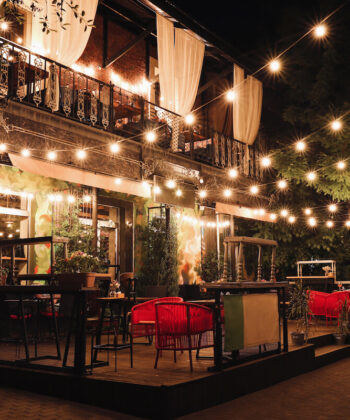 A charming restaurant exterior adorned with twinkling lights strung across the front, creating a warm and inviting atmosphere. - Hausion